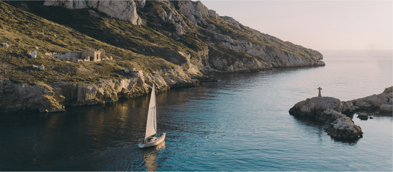 Landscape shot of a sailboat next to a rocky shore