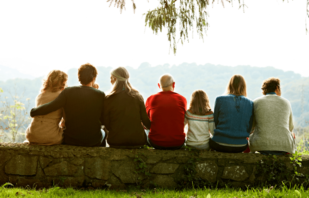 A family sitting on a stone wall, gazing at the beautiful scenery.