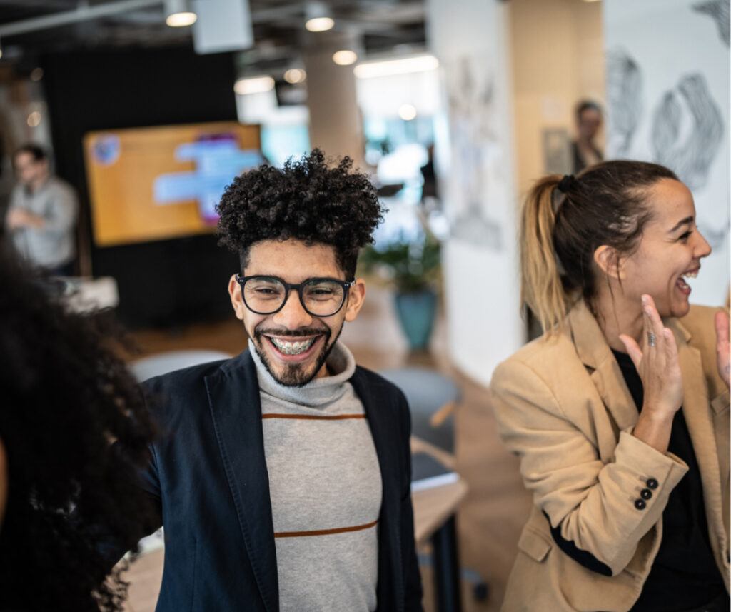 A group of people in an office laughing, enjoying a light-hearted moment together.