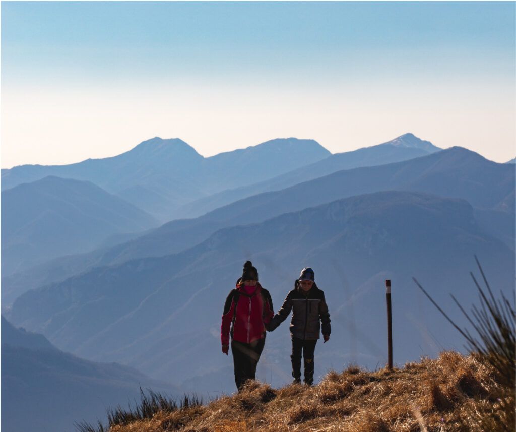 A man and a woman holding hands, conquering the heights of a beautiful mountain together.