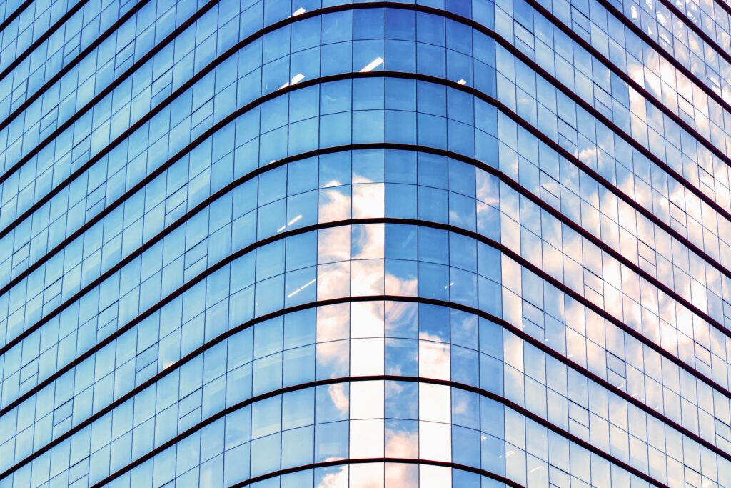 Photo of a modern building. Blue sky reflected on glass wall