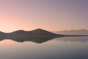 view of hills at sunset from across a calm body of water