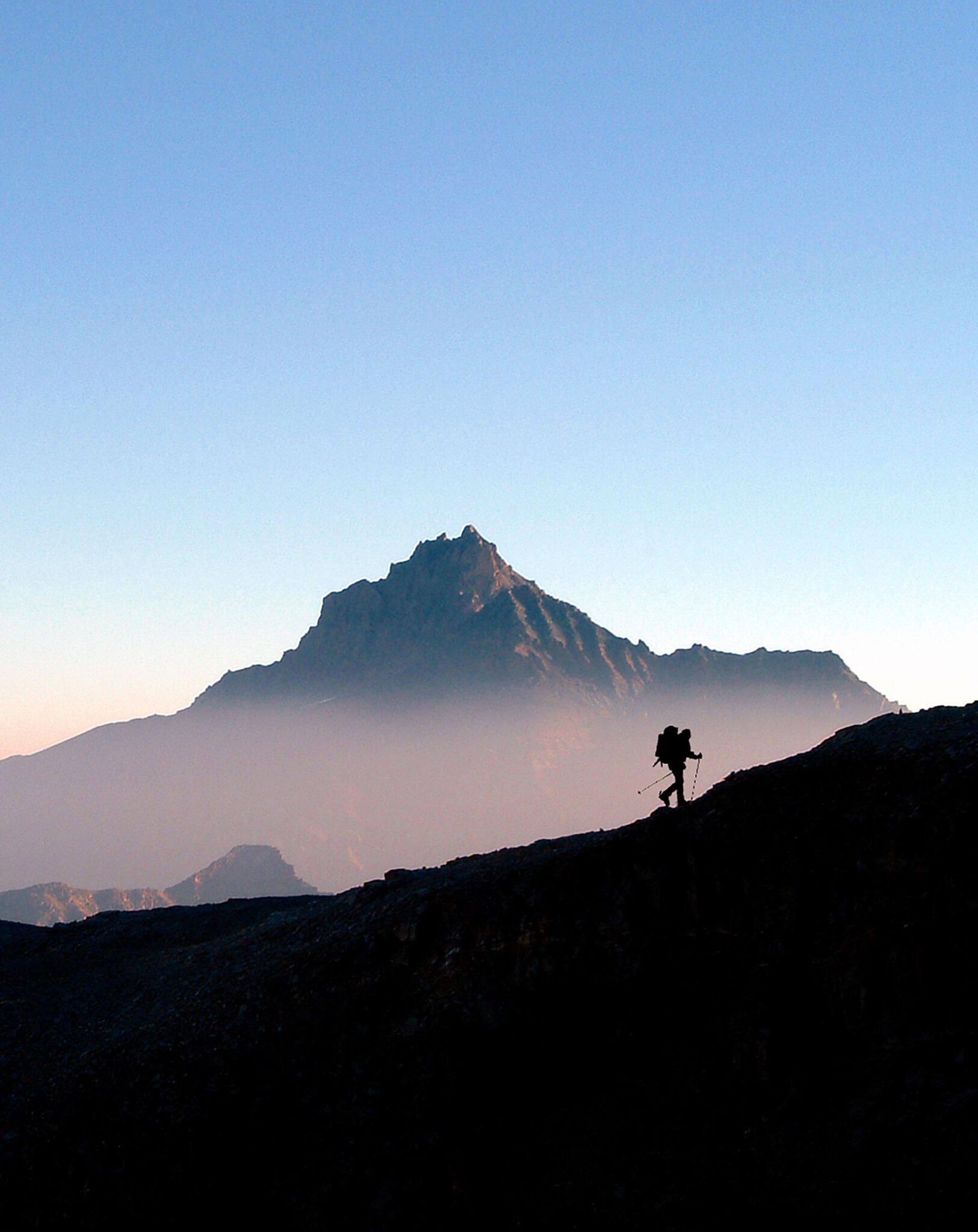 Man climbing mountain in hazy sky